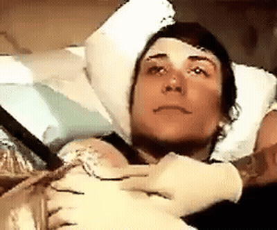 Man in Hospital Bed With Head Bandage and Gloves