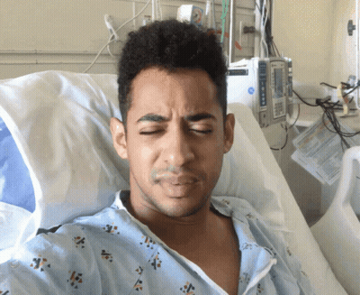 Man In Hospital Gown Lying In Bed Next To Medical Device GIF