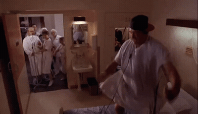 Man In Hospital Gown Surrounded By Doctors GIF