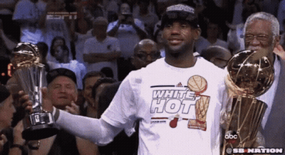 Man in Hot White Shirt Holds Two Trophies Before Crowd