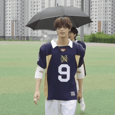 Man In Jersey Number 9 Holding Umbrella GIF