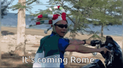 Man In Jester Hat And Sunglasses Saying It's Coming Rome On Beach GIF