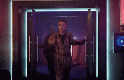 Man In Jumpsuit Walking Through Doorway In Dark Room GIF