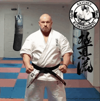 Man In Karate Uniform In Front Of Raychev Sign GIF