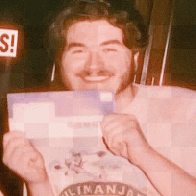 Man In Kilimanjaro Shirt Smiling Holding Purple Envelope GIF
