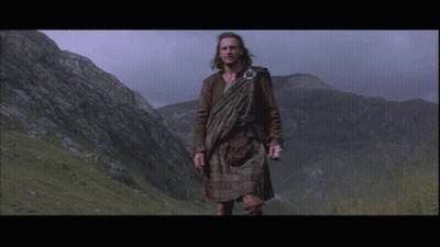 Man In Kilt In Field With Mountains GIF