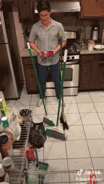 Man In Kitchen Holding Broom And Phone GIF