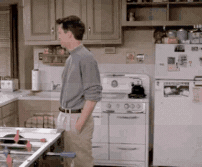 Man In Kitchen Next To Stove And Refrigerator GIF