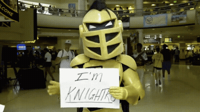 Man In Knight Costume Holding Sign Saying I'm Knightro GIF