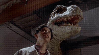 Man In Lab Coat Looking At Dinosaur GIF