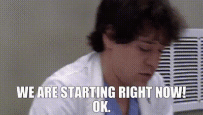 Man In Lab Coat Sitting In Front Of Fan GIF