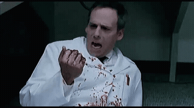 Man in Lab Coat Sitting With Bleeding Fingers