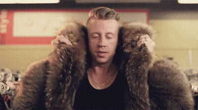 Man In Large Fur Coat Sitting In Store GIF