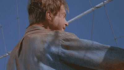 Man In Leather Jacket Against Blue Sky And Fence GIF