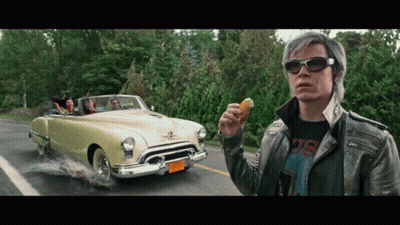 Man In Leather Jacket Holding Donut In Front Of Car With NC 88 License Plate GIF