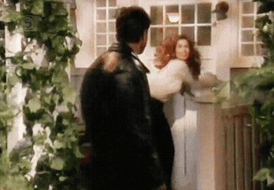 Man In Leather Jacket Holding Woman In Front Of Door GIF