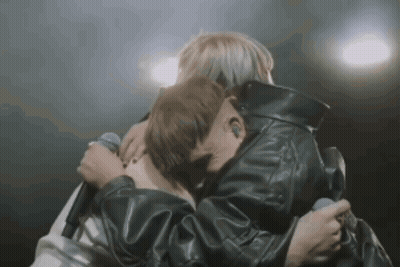 Man In Leather Jacket Hugging Another Man Holding Microphone GIF