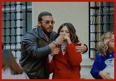 Man In Leather Jacket Hugging Woman In Red Coat GIF