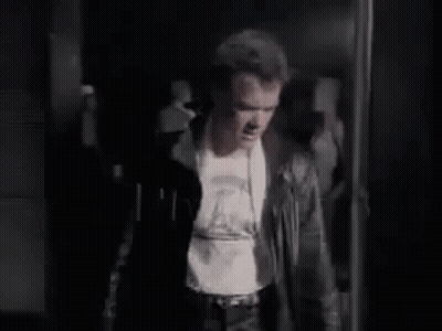 Man In Leather Jacket Standing In Dark Room GIF
