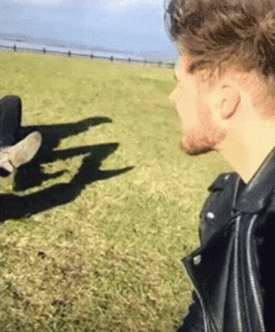 Man In Leather Jacket Standing In Grassy Field With Person GIF