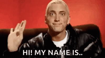 Man In Leather Jacket Waving On Couch GIF
