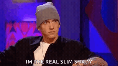 Man In Leather Jacket Waving On Couch GIF