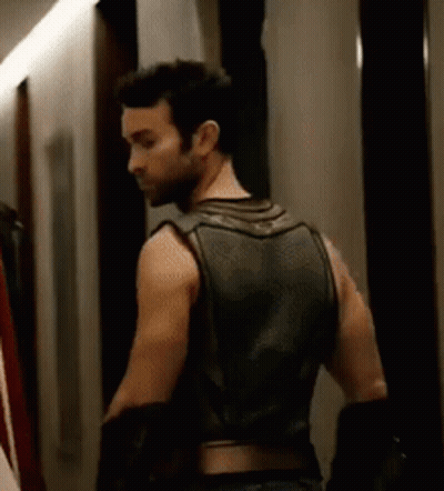 Man In Leather Vest Standing In Hallway GIF