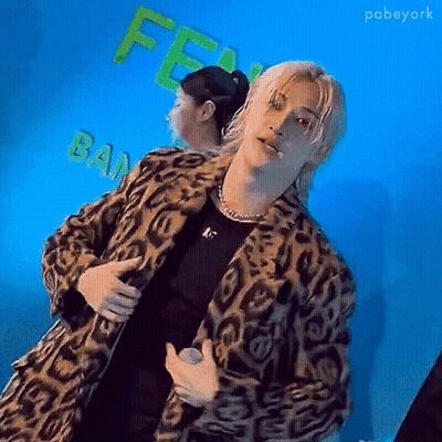 Man In Leopard Print Coat Holding Microphone And Woman With Ponytail GIF