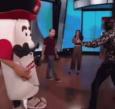 Man In Leopard Print Shirt Standing In Front Of Marshmallow Mascot GIF