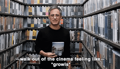 Man In Library Holding DVD Saying Walk Out Of The Cinema Feeling Like Growls GIF