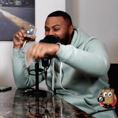 Man In Light Blue Sweatshirt Holding Wine Glass At Microphone GIF