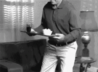 Man In Living Room Holding Tray With Food GIF