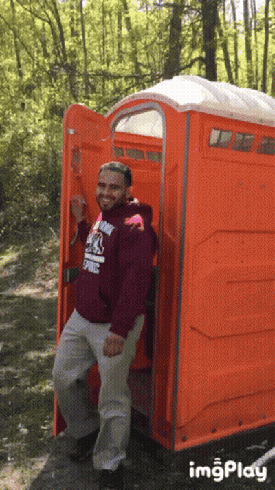 Man In Maroon Hoodie In Orange Public Toilet GIF