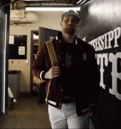 Man In Maroon Jacket And White Pants Walking Past Mississippi GIF