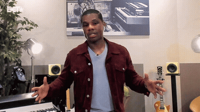 Man In Maroon Jacket Standing In Front Of Keyboard And Guitar GIF