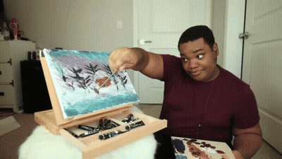 Man In Maroon Shirt Painting On Easel GIF