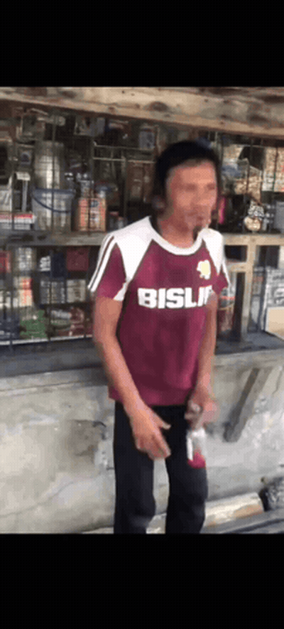 Man in Maroon Shirt Saying Bisli in Front of Store