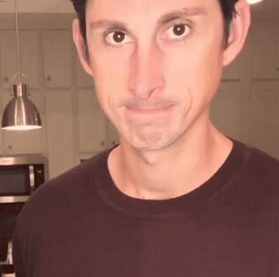 Man In Maroon T-Shirt Looks At Camera GIF