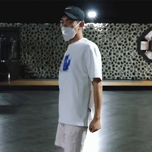 Man In Mask And Hat Standing In Dark Room GIF