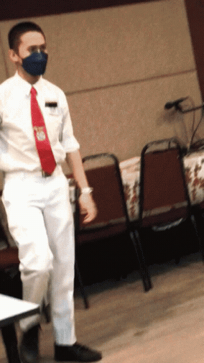 Man In Mask And Red Tie Standing At Table GIF