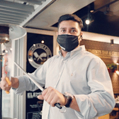 Man In Mask Holding Knife In Front Of Elec Sign GIF