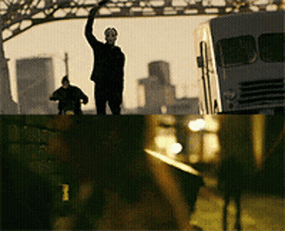 Man In Mask On Bridge With Hand Up GIF