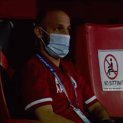 Man In Mask Sitting On Red Chair With No Sitting Sign GIF