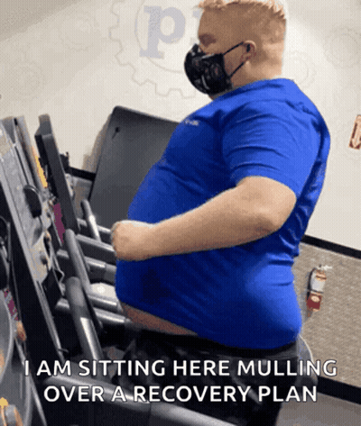 Man In Mask Sitting On Treadmill Saying I Am Sitting Here Mulling Over A Recovery GIF