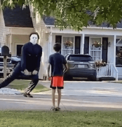 Man In Mask Standing On One Leg In Front Of House GIF