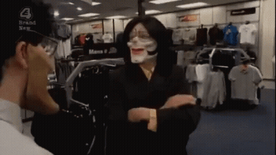 Man In Mask Talking To Another In Clothing Store GIF