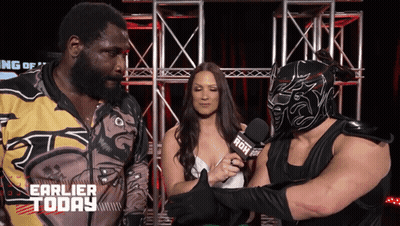 Man In Mask Talks To Woman With Microphone Saying Earlier Today GIF