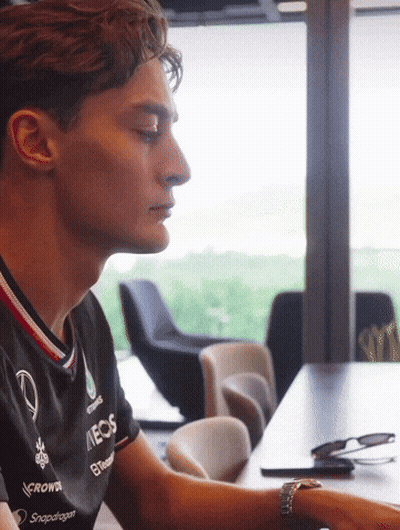 Man In Meos Shirt Sitting At Table GIF