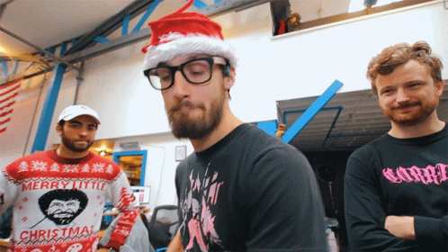 Man In Merry Little Christmas Sweater Next To Two Men GIF