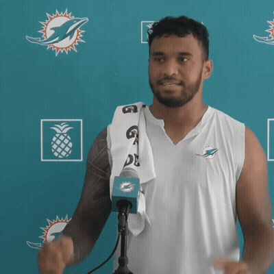 Man In Miami Dolphins Shirt In Front Of Blue Wall GIF